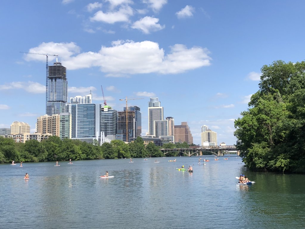 City skyline with skyscrapers and a lake. People kayaking on the lake.