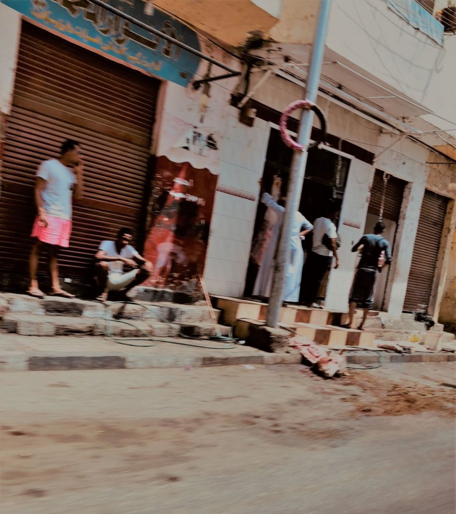 The streets of Luxor, Egypt. Young men stand and sit near a freshly butchered cow on the street.