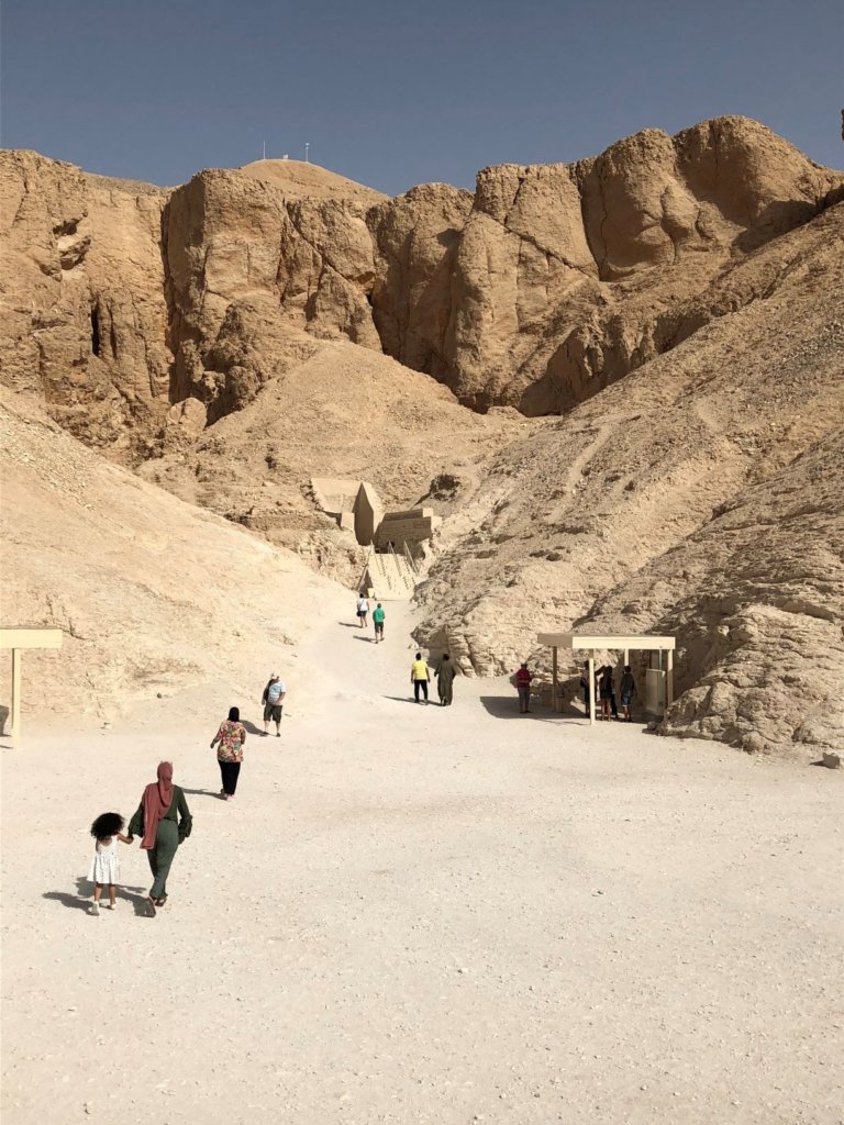 The Valley of the Kings near Luxor, Egypt. People walking in sand towards sand cliffs and tombs of the Egyptian pharoahs.