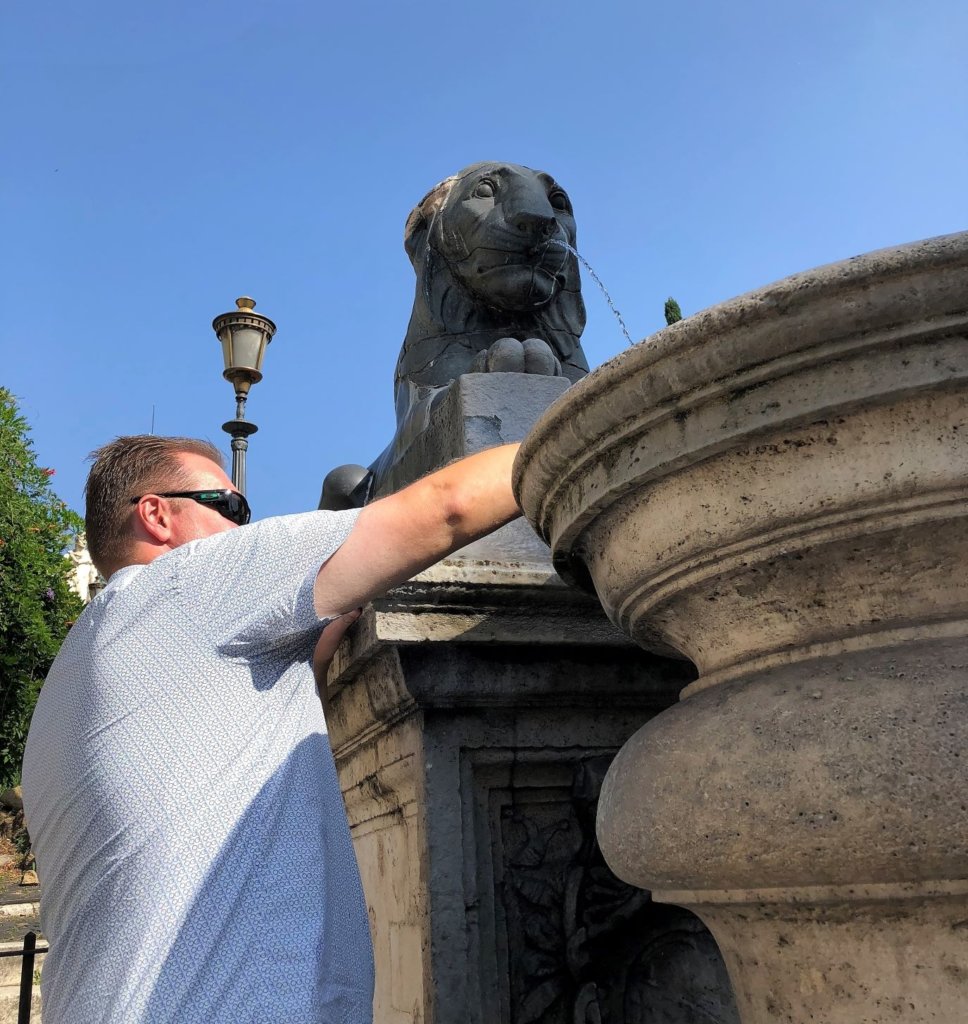 Filling a water bottle from a lion fountain at Capitoline Hill in Rome