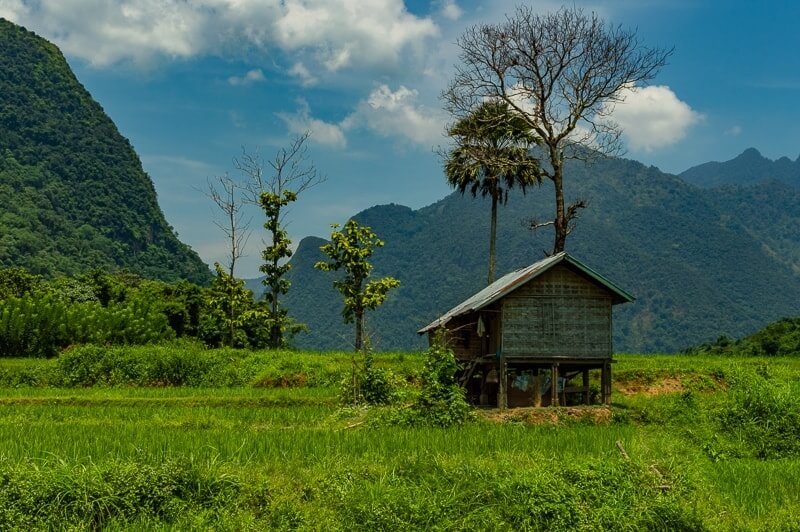 Green valley in Laos with a small house on stilts