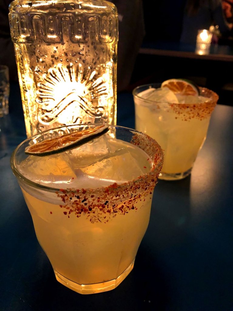 Margaritas with house made spice rimmed glass illuminated by a candle