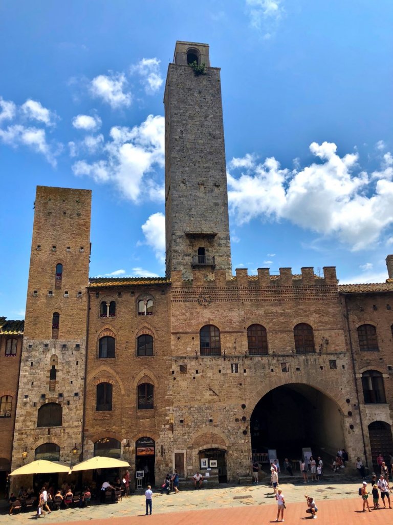 Piazza Duomo at San Gimignano with two tall towers and people in the square