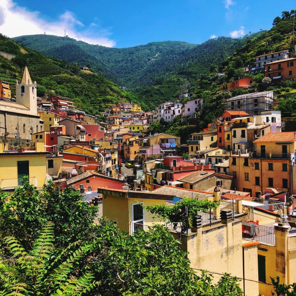 colourful houses line the green hills of riomaggiore cinque terre