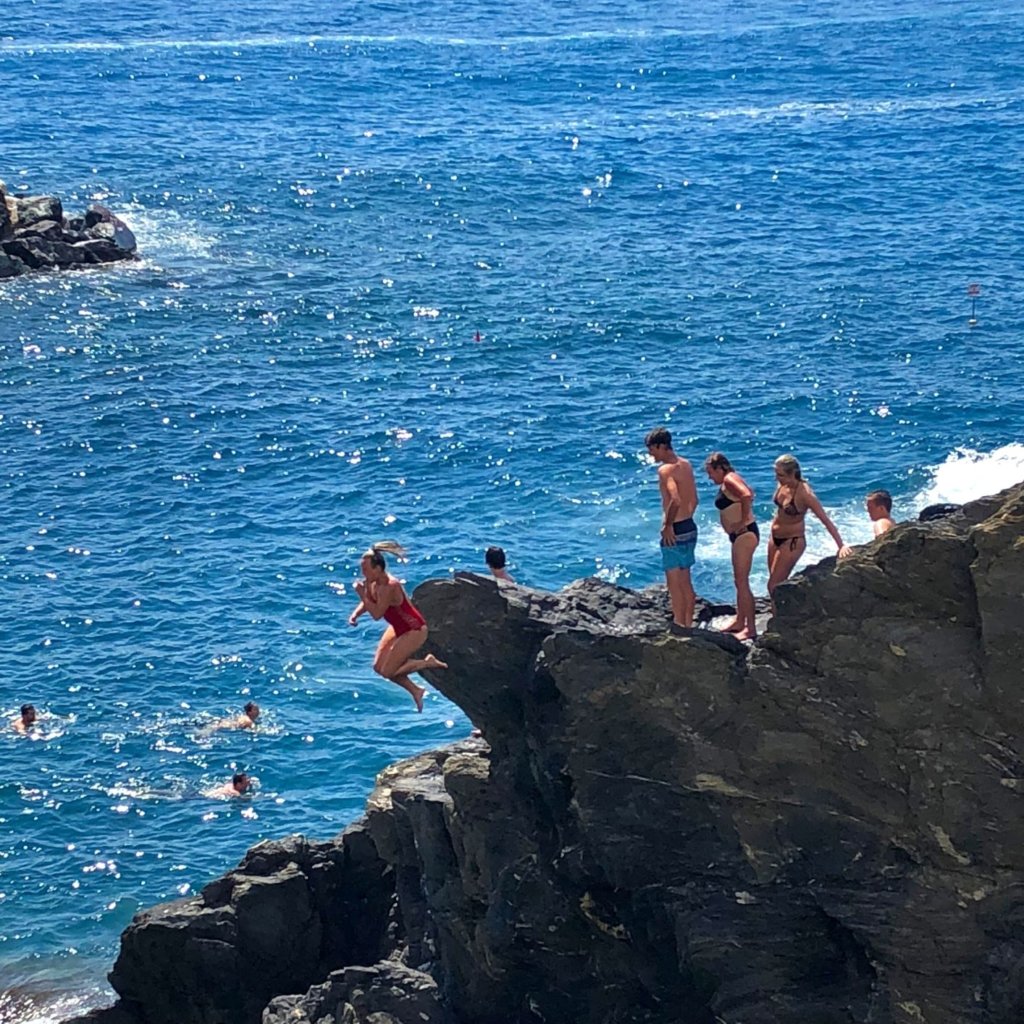 Girl jumping off rocks into the water in manarola cinque terre