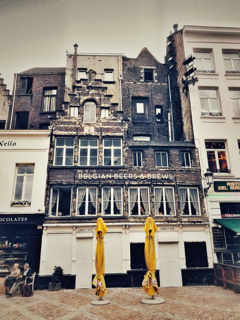 Street of Antwerp, Belgium featuring Flemish architecture, a building with Belgian beers and brews and yellow umbrellas