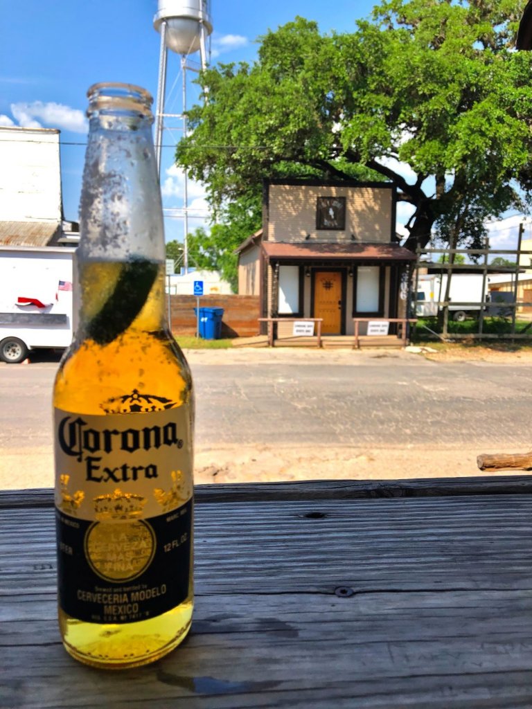 Corona Beer rimmed with salt and sitting on a wooden outdoor bar