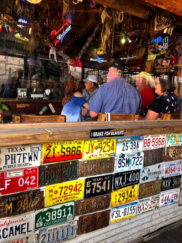 people sitting at a table in the bar with colourful license plates on the wall