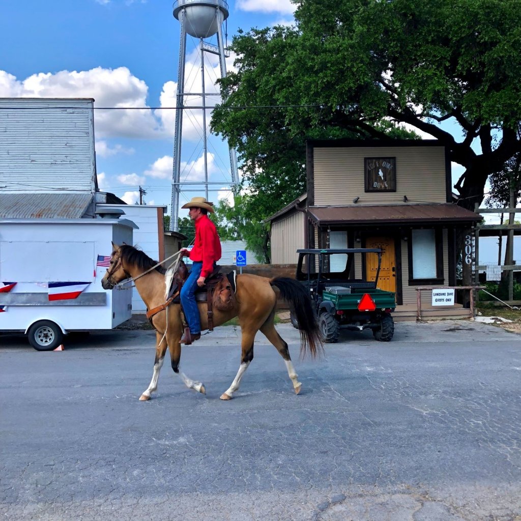 cowboy rides a horse down the street of Bandera