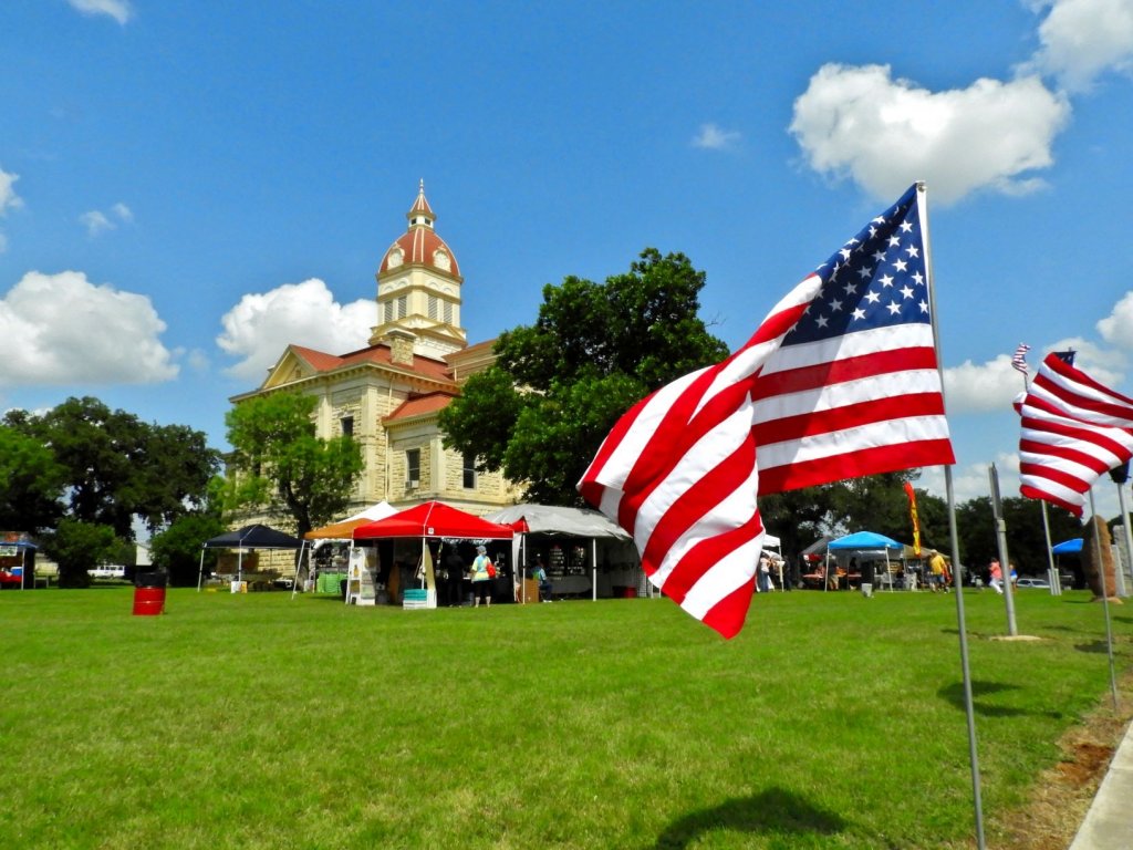 Courthouse lawn with American flags and vendors set up in the green grass.