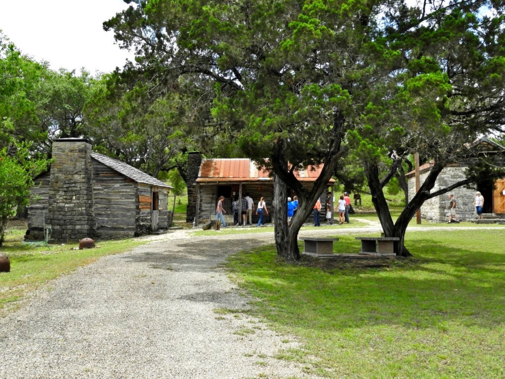 old wooden cabins and people at a fort in Texas