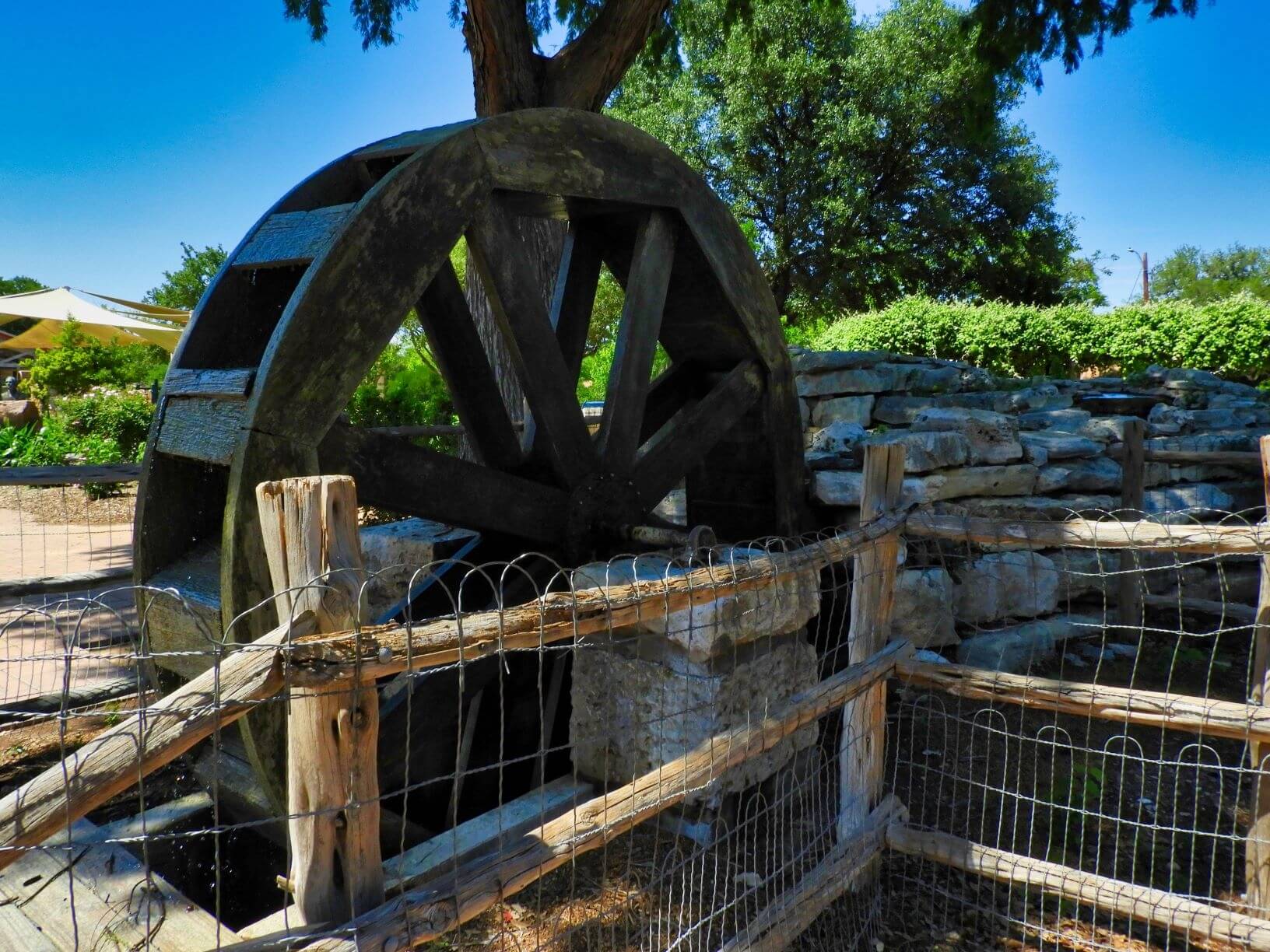 a wooden water wheel surrounded by fencing