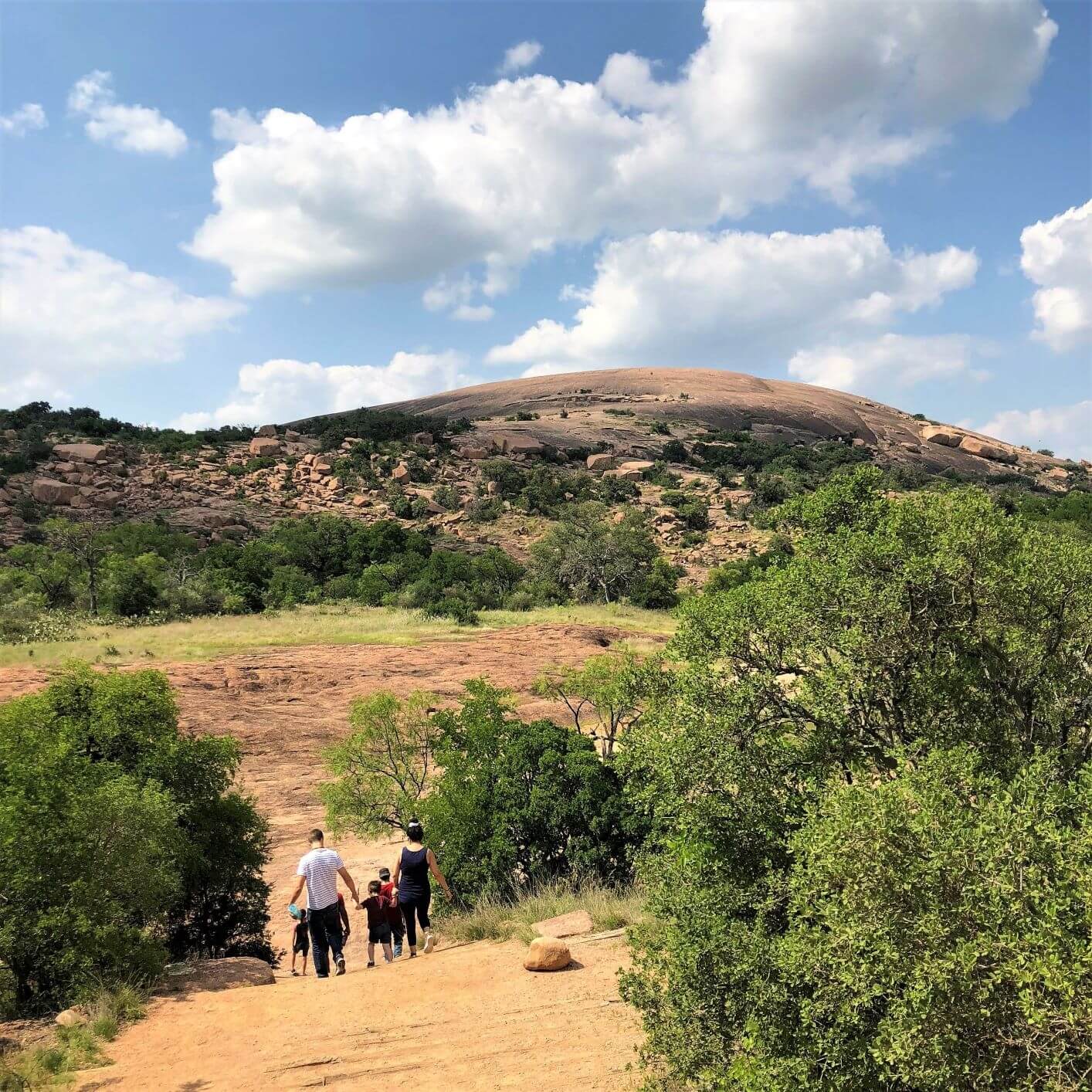 family of hikers on their way to large pink granite dome in Enchanted Rock State Natural area