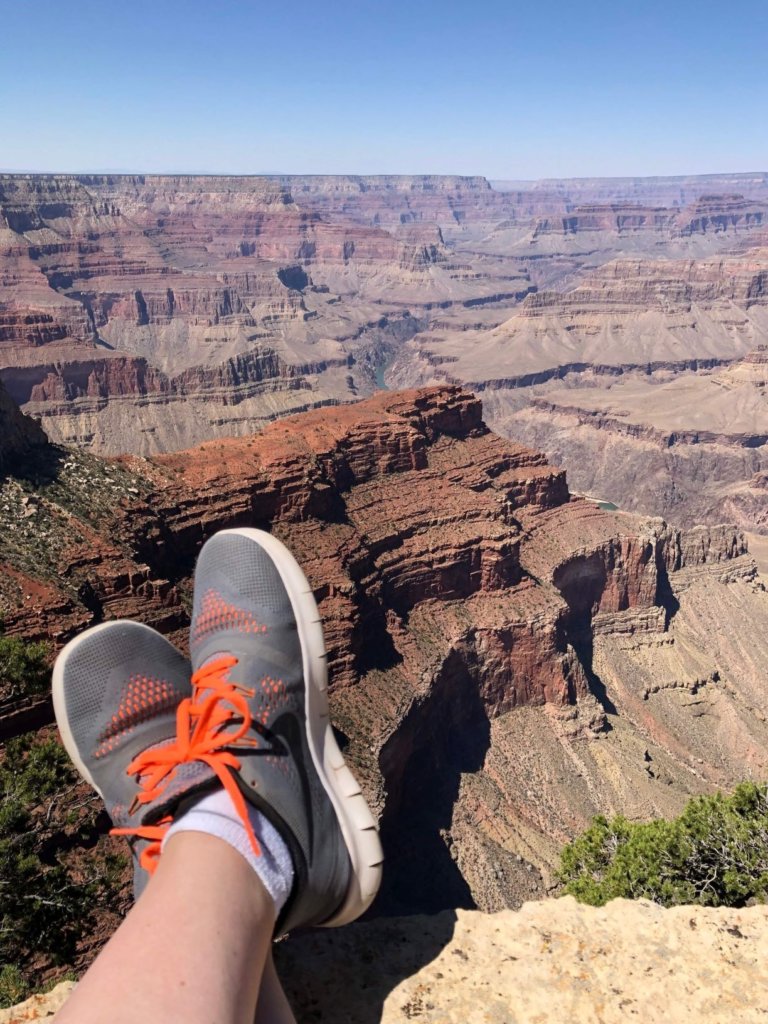 shoes with orange laces hanging on the edge of the grand canyon