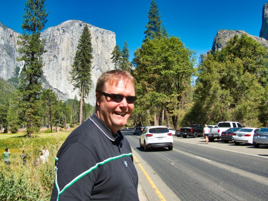 Man standing on a road smiling in Yosemite National Park by El Capitan