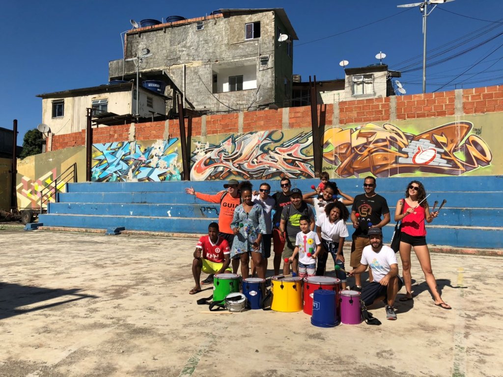 people standing around painted drums on streets with graffiti