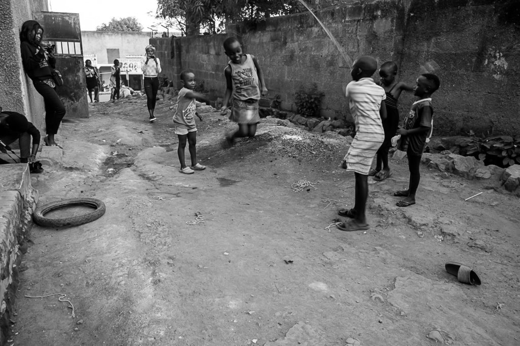 kids jumping rope in an alley while people take pictures