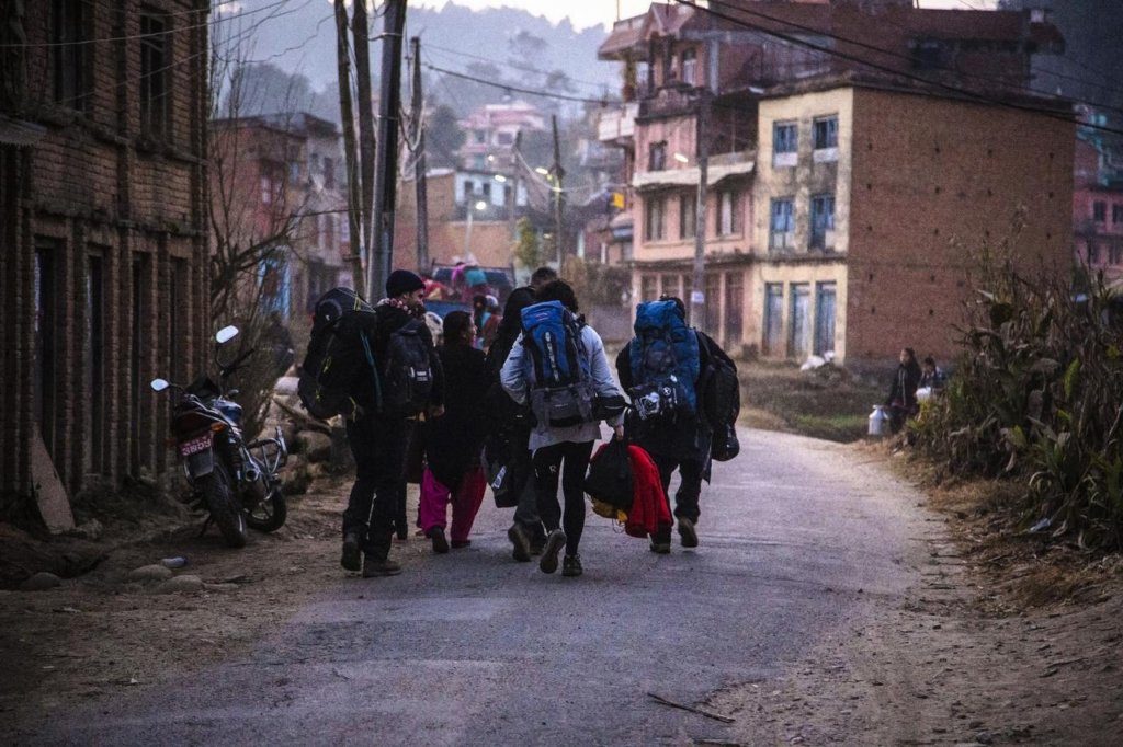 people walking down a street with backpacks in an impoverished neighbourhood