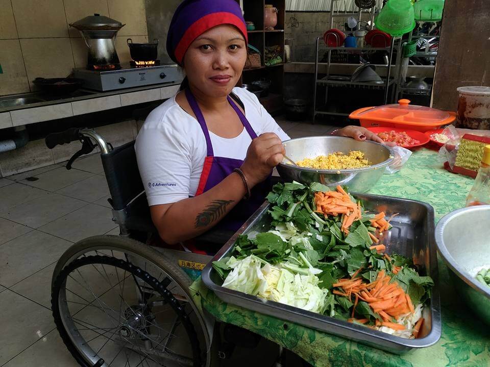 woman sitting in a wheelchair preparing a meal of fresh vegetables.