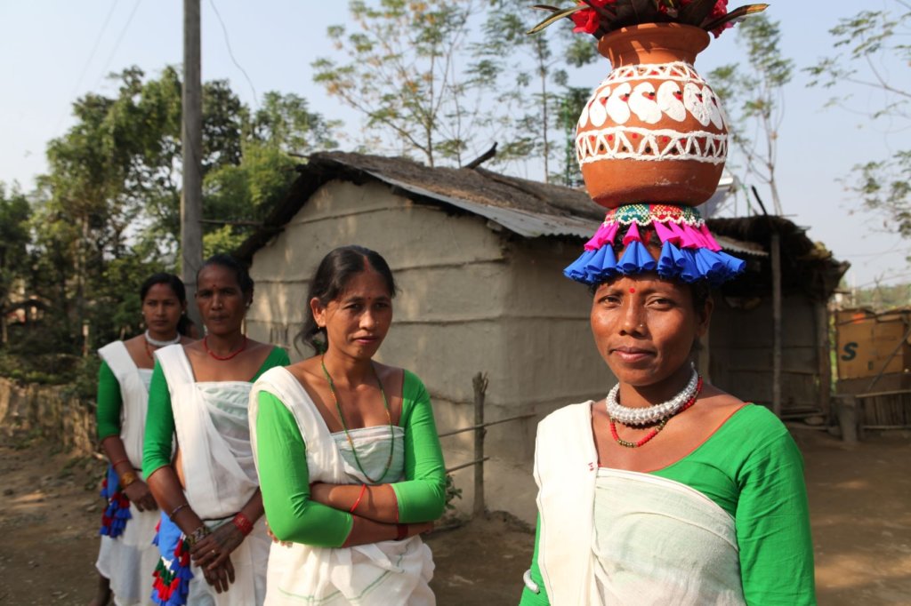women in colourful clothing carrying jugs on their heads