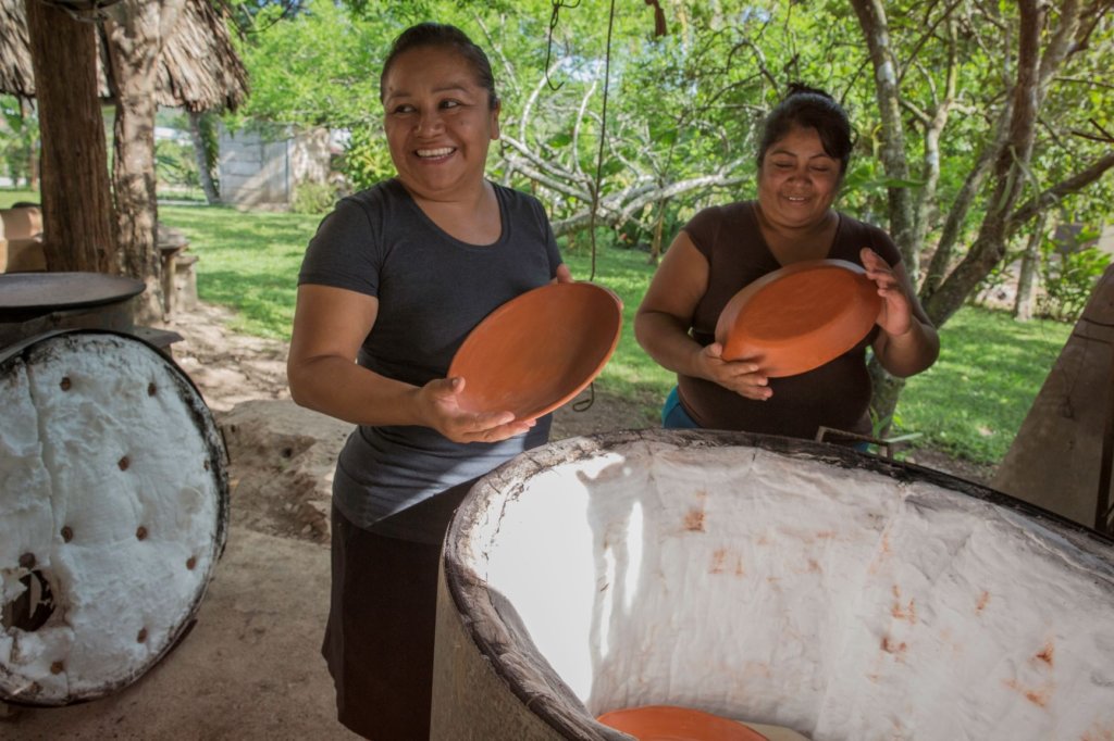 women smiling standing around a pottery kiln