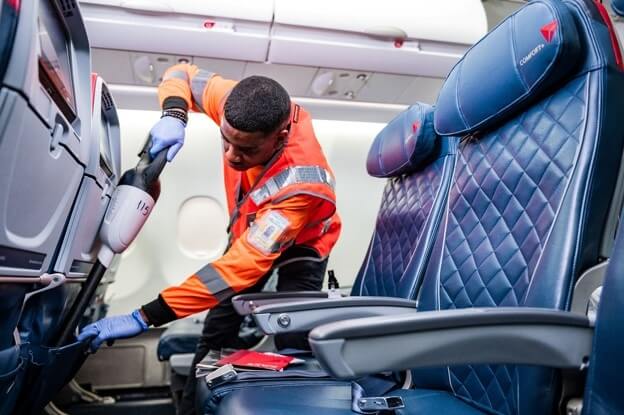 man disinfecting seat pockets in an airplane